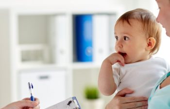 infant held by his mom while a doctor takes notes, 