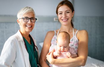 A doctor and a mother holding her baby in her arms., 